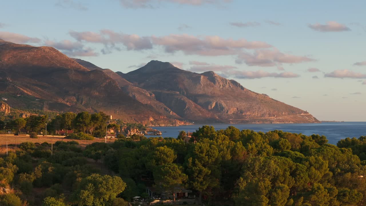 Descending aerial drone revealing Guidaloca Beach and Sicilian coast, Sicily, Italy at sunrise, showing cliffs, vast blue ocean, and natural scenery