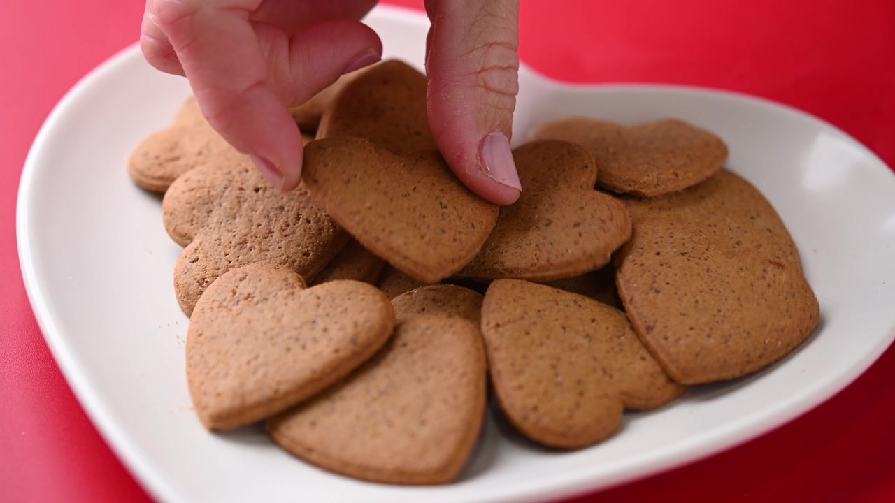 Hand Taking Heart Shaped Valentine Cookie from Plate