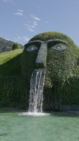 giant face water fountain sculpture in a park