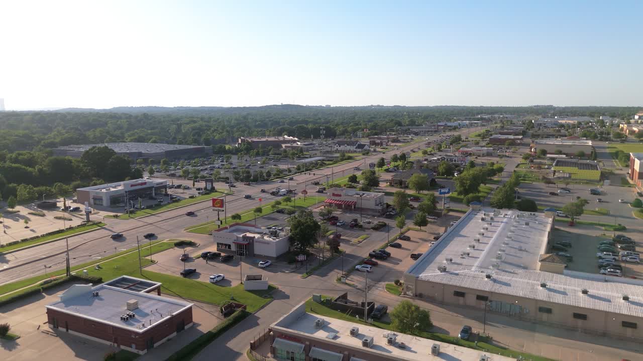 Vista de drone sobre a South Memorial Drive, em South Tulsa: onde vitrines, trânsito e um toque de verde se encontram sob um vasto céu de Oklahoma, combinando a agitação local com o charme suburbano e tranquilo.