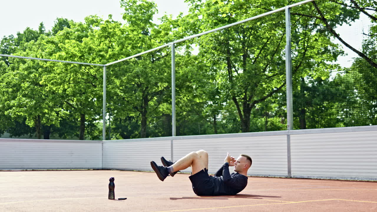 Un uomo muscoloso che si allena su un campo di allenamento all'aperto. L'uomo indossa pantaloncini neri e scarpe da ginnastica. Un atleta nel parco. Stile di vita sano.