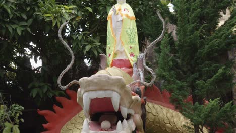 white buddha statue on the head of dragon sculpture holding pearl on its mouth