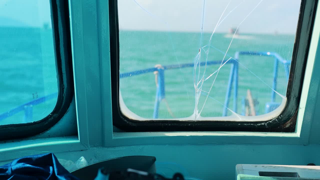 A fishing boat navigates the ocean with a cracked windscreen, capturing the serene seascape of Phuket, Thailand