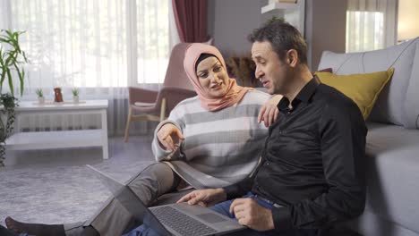 Muslim-woman-wearing-hijab-and-her-husband-looking-at-laptop-at-home.