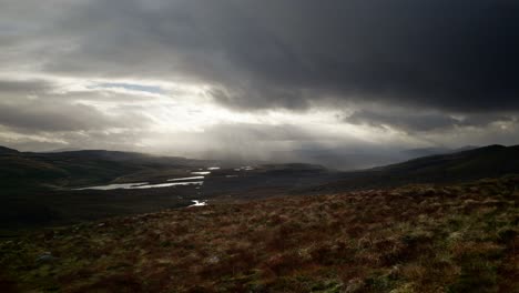 fierce winds and shafts of light pierce dark clouds to highlight a landscape of fresh water lochs nestled in the mountains of scotland