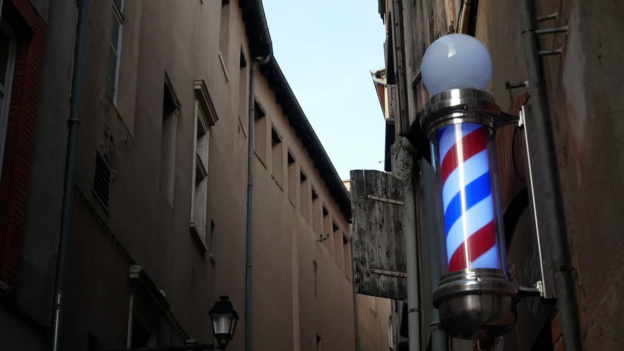 un poste de barbería giratorio tradicional en una esquina de la ciudad al atardecer - aislado
