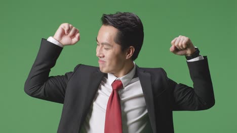 an asian business man smile and flex muscle on green screen background in the studio