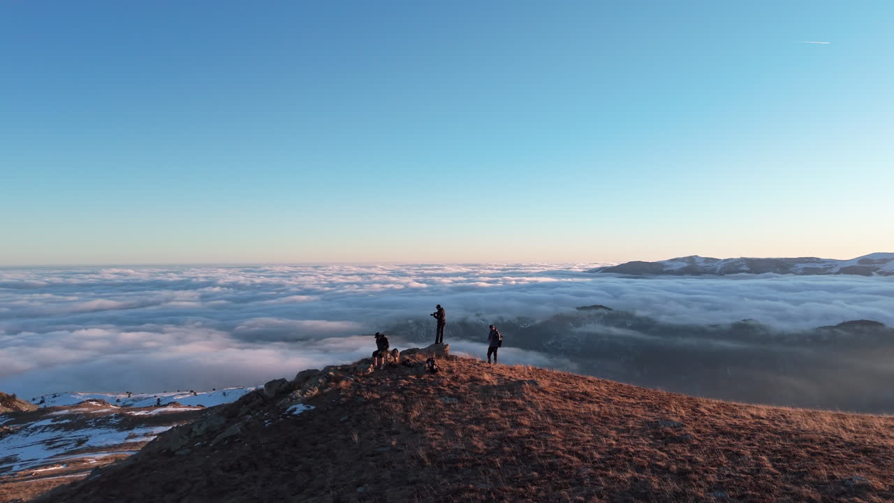 Escursionisti raggiungono una cima di montagna all'alba, godendosi una vista mozzafiato sull'oceano.