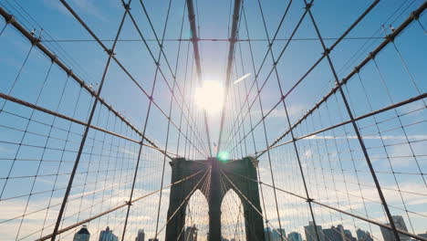 Spaziere-Entlang-Der-Brooklyn-Bridge-Von-Manhattan-Nach-Brooklyn-Die-Sonne-Im-Zenit-Scheint-Im-Rahmen-Pov