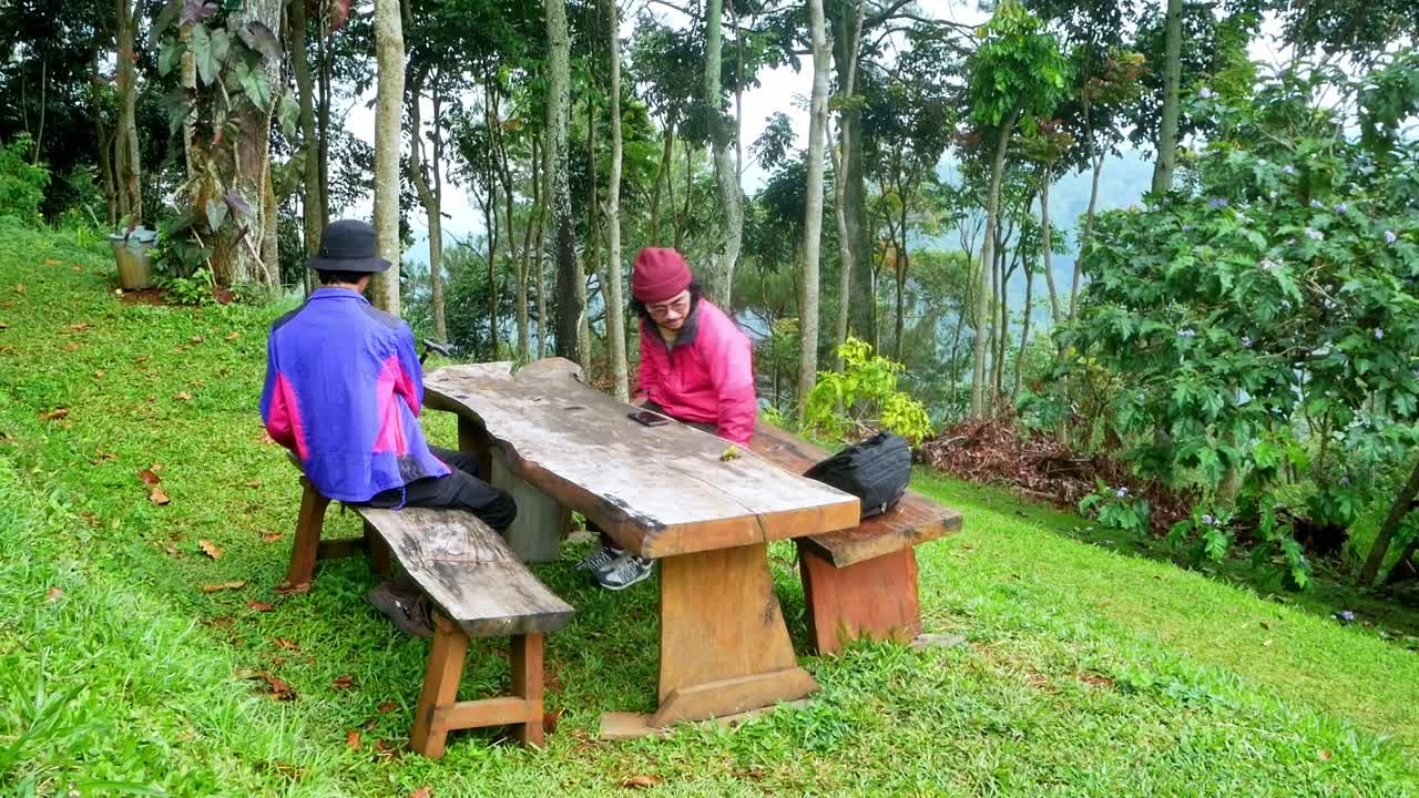 Exhausted hikers take rest on table while walking at forest