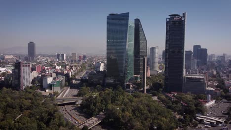 group of skyscrapers on paseo de la reforma avenue in mexico city taken with a drone on a sunny and clear day, next to it is a large avenue with several cars circulating