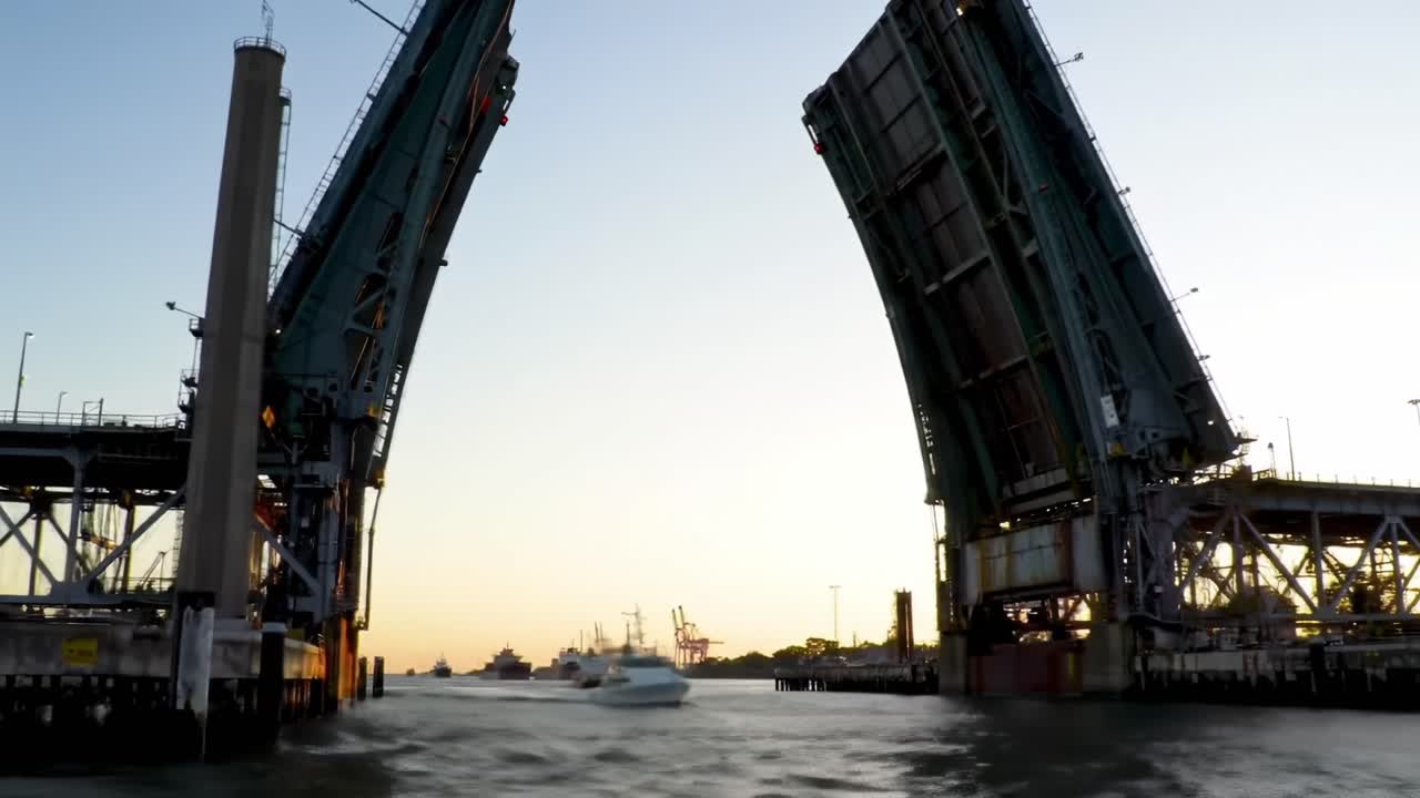 Majestic View of a Drawbridge Opening at Sunset, Framing the Harbor with Ships Silhouetted Against the Colorful Evening Sky