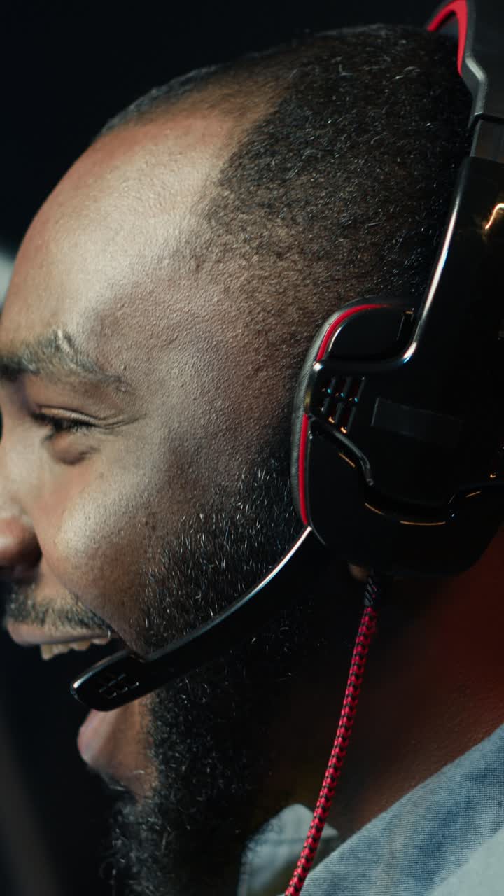 Vertikal video: Mann ler mens han spiller på gaming-PC og snakker med kamerater