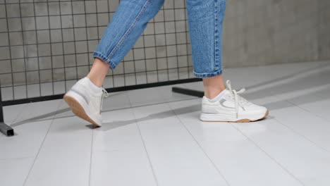 girl in short blue jeans and light white sneakers. trendy sport shoes presentation in photo studio.