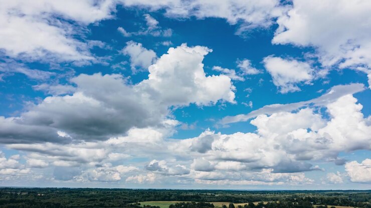 Luchtfoto drone hyperlapse-weergave van donzige witte wolken die drijven over een helderblauwe lucht en een verre groene plattelandshorizon