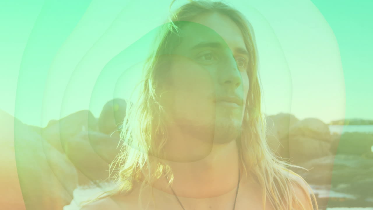 Standing by rocks, man with long hair overlaid with colorful animation shapes