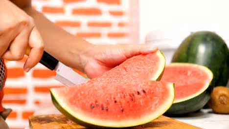 hands of women using a knife slice the water melon into pieces on wooden board in a kitchen