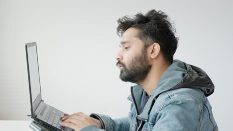 joven estudiante indio tomando una prueba en la computadora portátil, luchando y renunciando