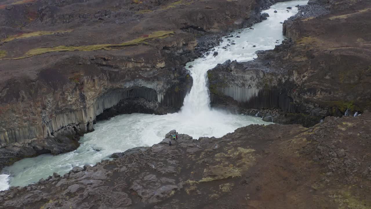 toma aérea hacia atrás de la cascada aldeyjarfoss entre montañas rocosas de islandia