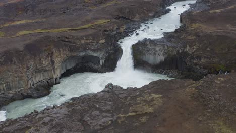 Toma-Aérea-Hacia-Atrás-De-La-Cascada-Aldeyjarfoss-Entre-Montañas-Rocosas-De-Islandia