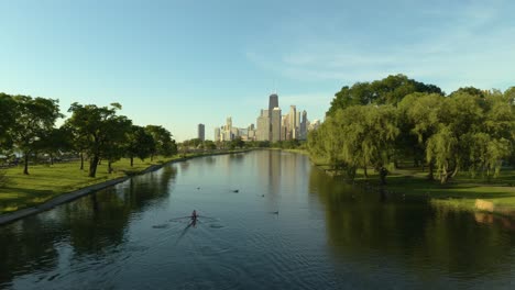 drone tracking person rowing in water with chicago skyline in background during warm summer day