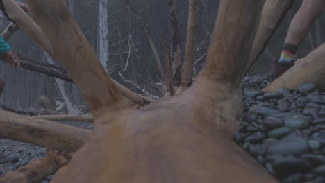 Close-up-of-boots-as-two-women-on-a-backpacking-trip-make-their-way-over-a-downed-tree-on-the-beach-on-the-Olympic-Peninsula---Washington-State