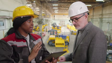 female factory worker and engineer discussing something on tablet