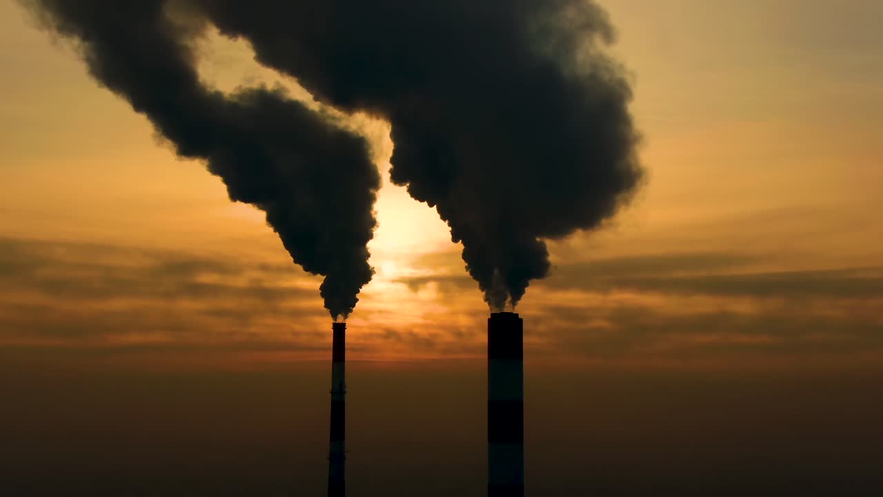 Power Plant emissions seen above the city during sunrise. Environmental pollution. Factory pipe polluting air.Panorama sunset. Smoking pipes Aerial view,