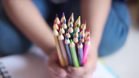 child holding a bunch of colored pencils