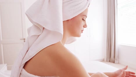 Woman-applying-moisturizer-cream-on-her-leg-in-bedroom