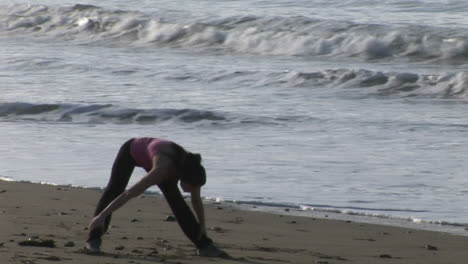 mujer estirándose en la playa