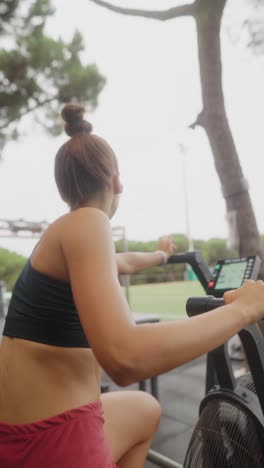 woman exercising on an air bike at an outdoor gym