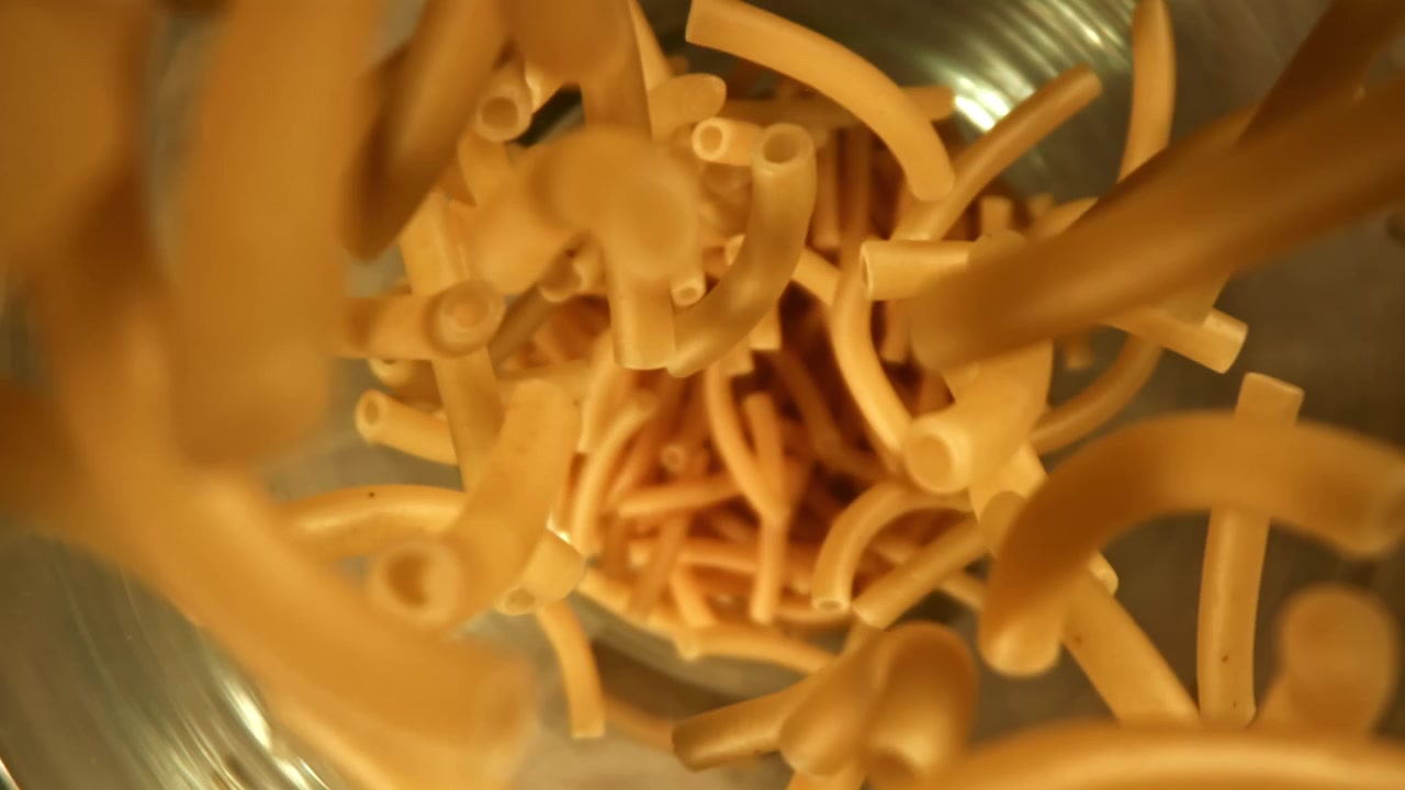 Maccheroni secchi che cadono in una ciotola al rallentatore