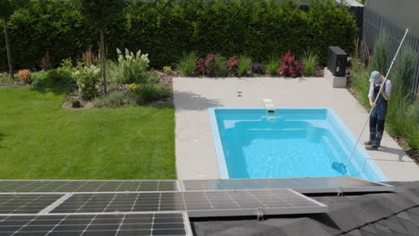 a worker catches garbage in the pool with a net. maintenance and cleaning of swimming pools