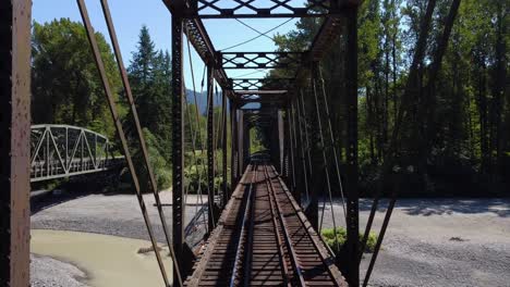 Drone-flying-through-a-Railroad-Bridge-above-the-Nooksack-River-in-the-Cascade-Mountains,-Washington-State