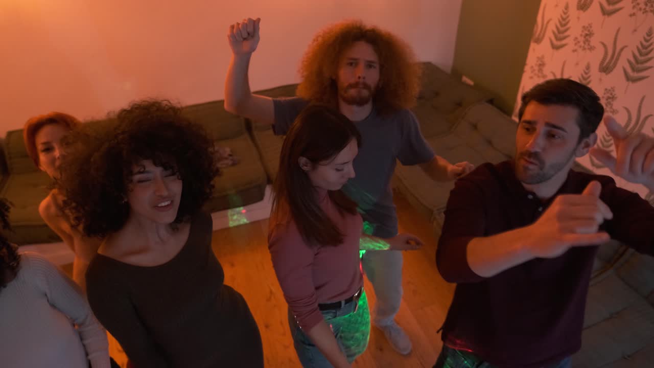 Portrait of happy friends grooving to music while enjoying weekend party in living room