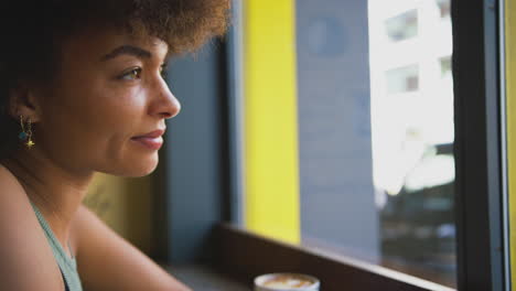 female customer in coffee shop window working writing in notebook