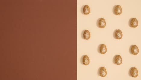 easter pattern with golden glitter eggs appear on nude brown background. stop motion flat lay