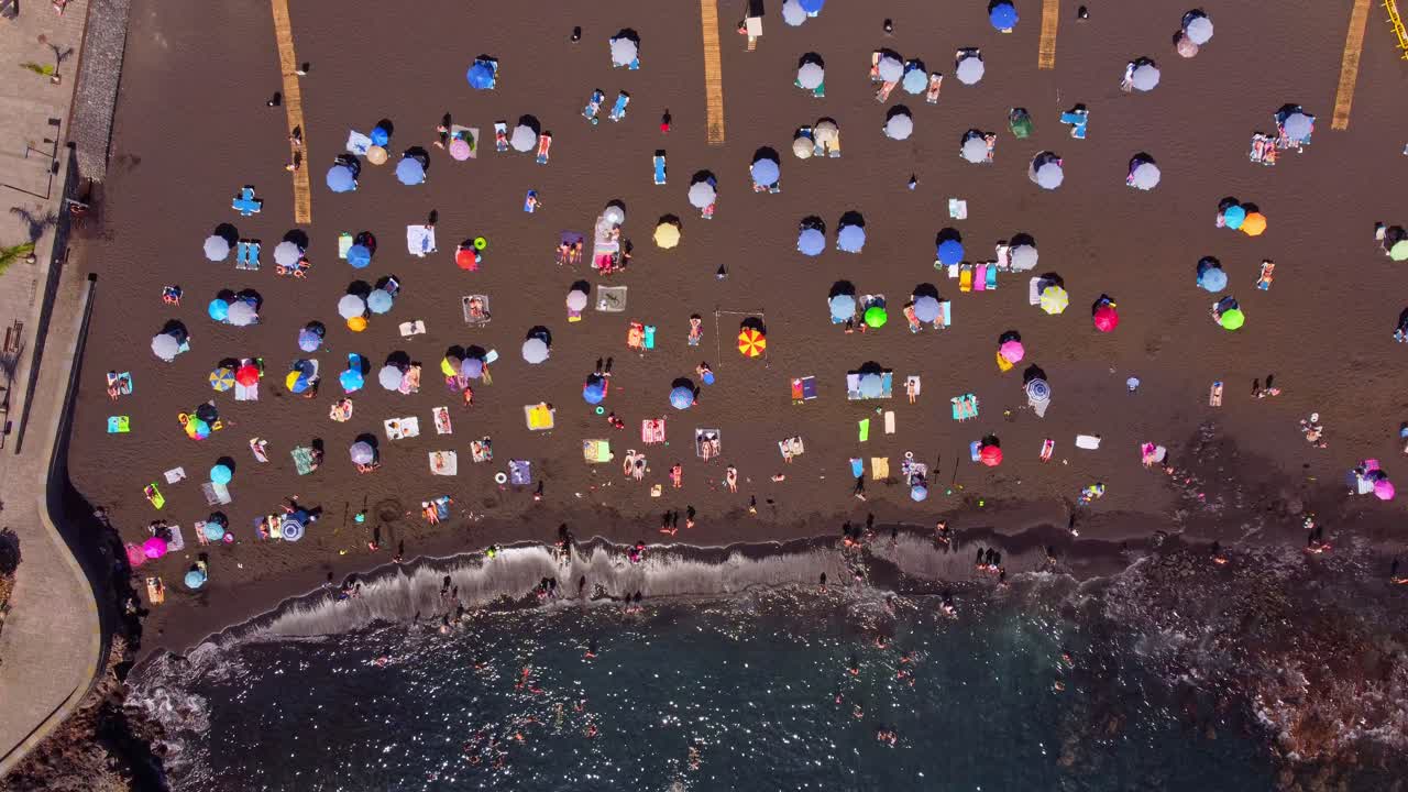 paraguas coloridos en una playa de arena en tenerife, capturados desde arriba hacia abajo