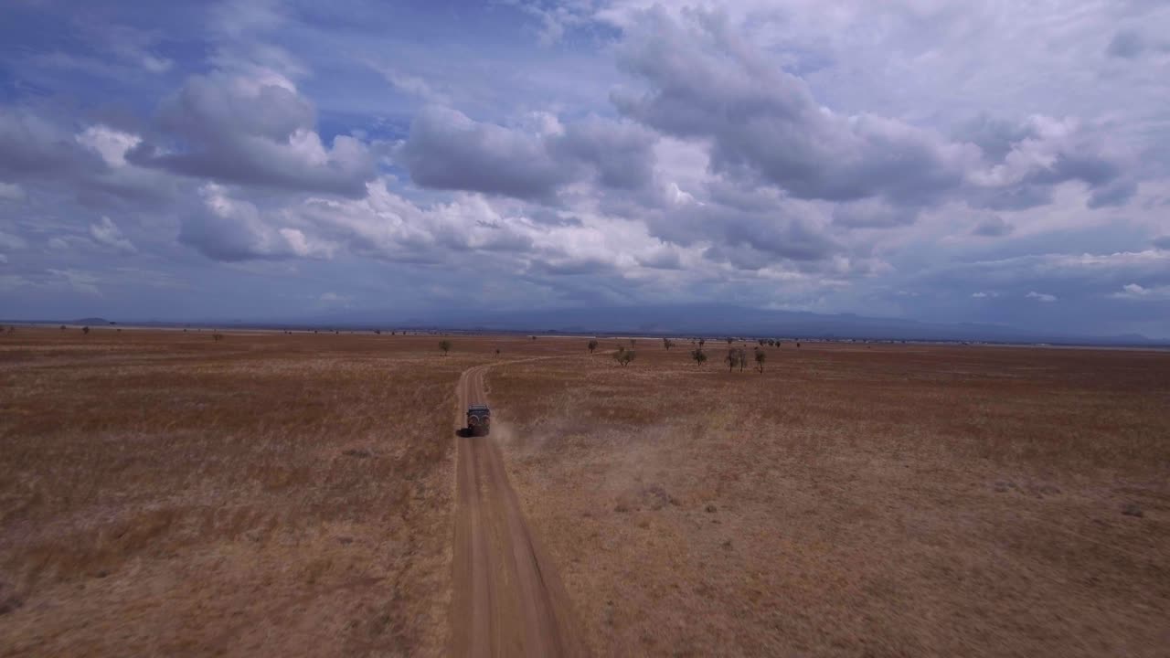 Drone shot of SUV Driving through African savannah. Rangers tracking Poachers. Tourists on safari