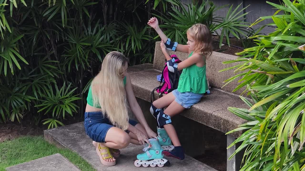 Mother helping daughter put on roller skates