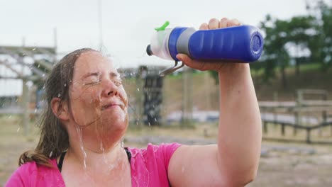 Caucasian-woman-pouring-water-on-her-face-at-bootcamp