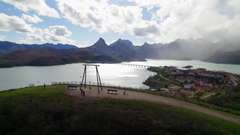 una foto aérea de los padres balanceando a su hijo en el columpio en el mirador de riaño, un pueblo en león, españa, en la orilla de un gran embalse en las montañas cantábricas.