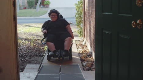 muscular dystrophy adolecsent in wheelchair approaches handicap ramp into house