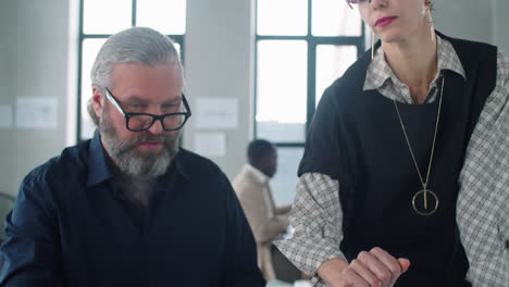 Businesswoman-Discussing-Project-on-Laptop-with-Senior-Male-Colleague