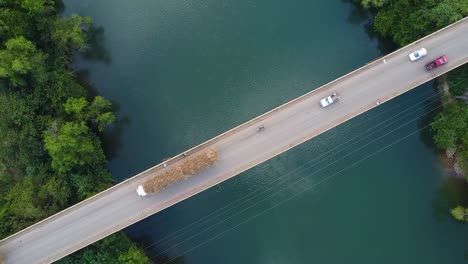 thin bridge over a cyan river with traffic traveling over