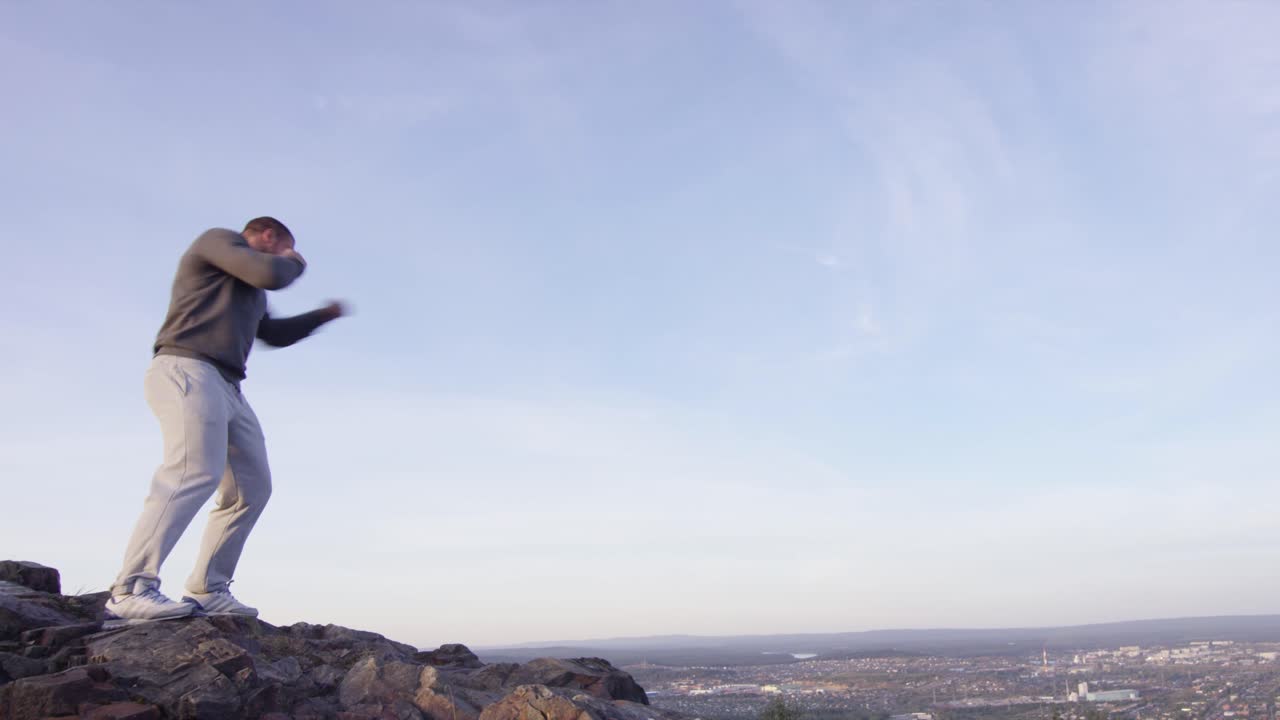 도시 전망 을 가진 산 꼭대기 에서 권투 하는 사람