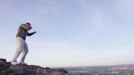 hombre boxeando en la cima de una montaña con vista a la ciudad