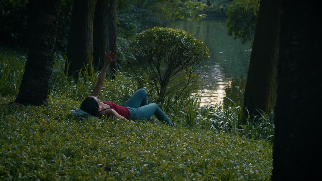 Woman Relaxing in a Park by a Pond