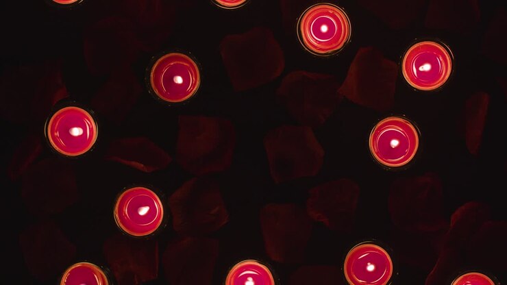 Overhead Shot Of Romantic Lit Red Candles On Background Covered In Rose Petals With Copy Space